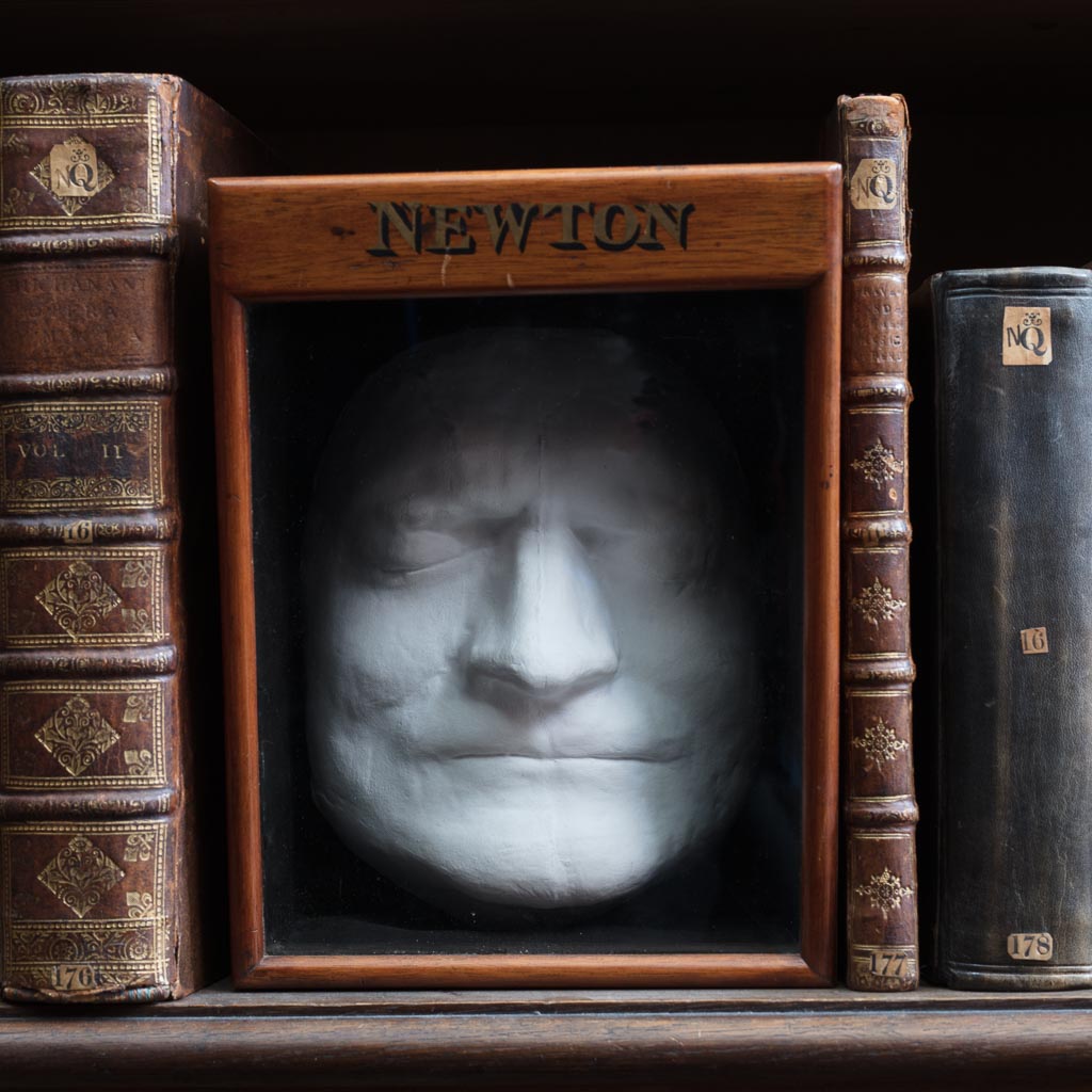 Isaac Newton's Death Mask sitting on a shelf in the Wren Library, Trinity College, Cambridge and nestled between some of Newton's personal books.
